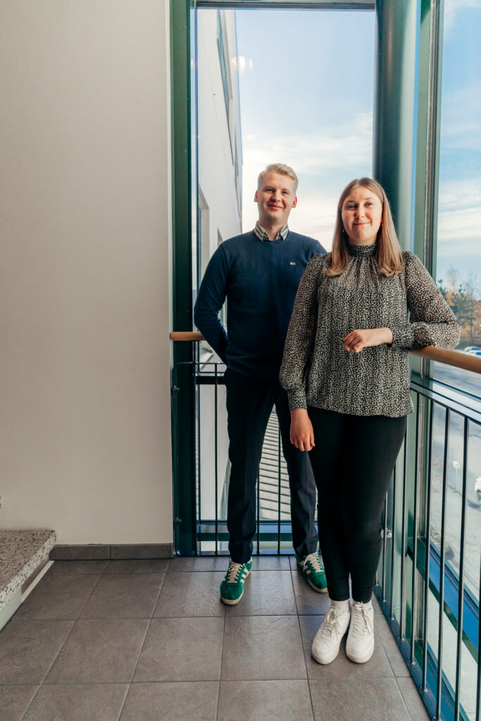 Kuvassa seisoo kaksi nuorta työntekijää ja hymyilee kameralle.